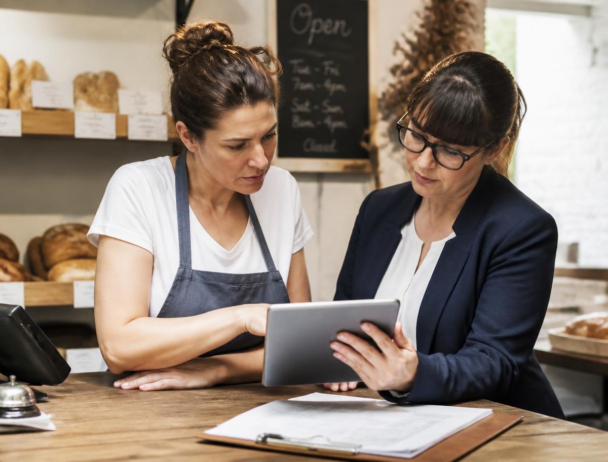 Accountant reviewing bookkeeping on a tablet with a bakery owner